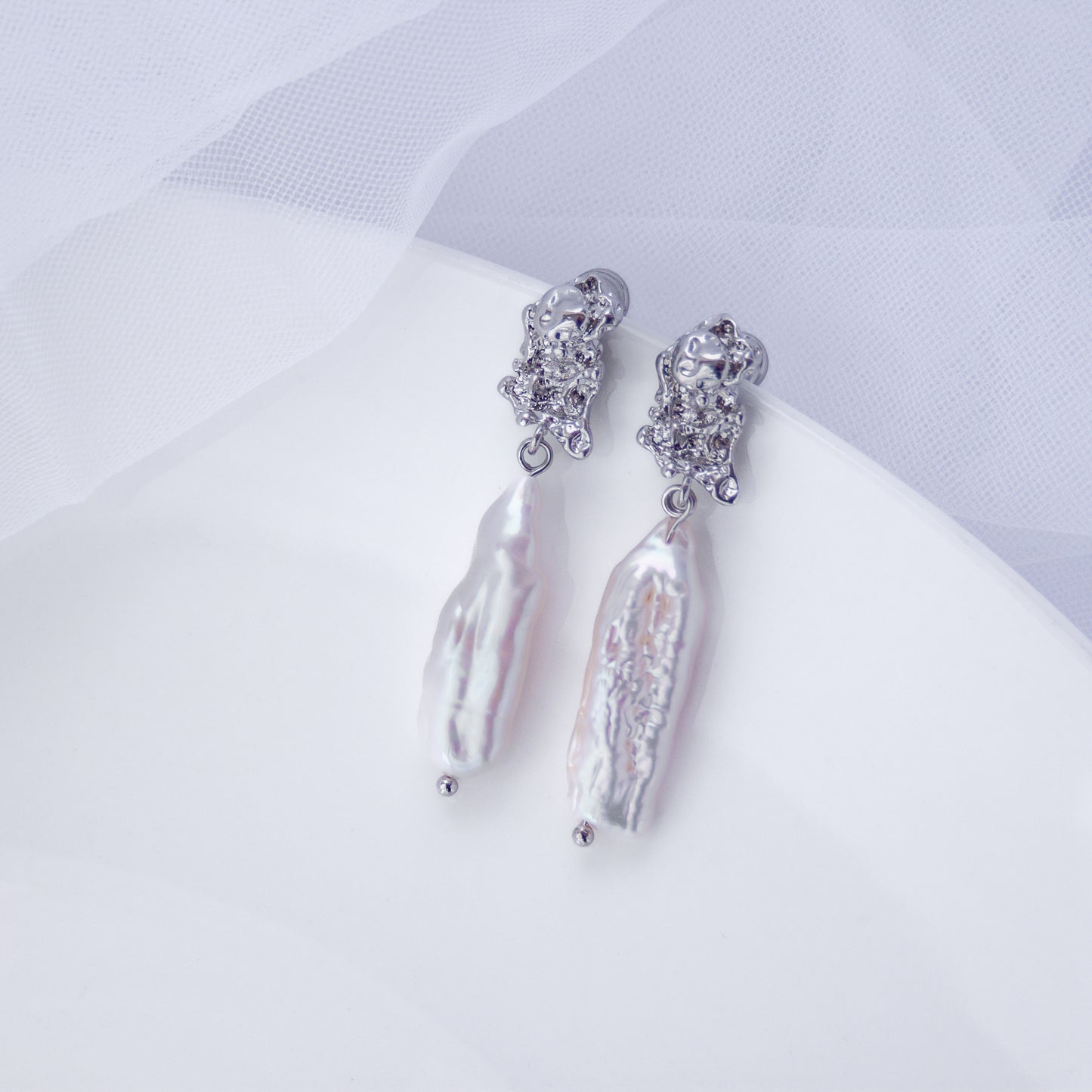 Long drop earrings with natural Biwa baroque freshwater pearls on a white background