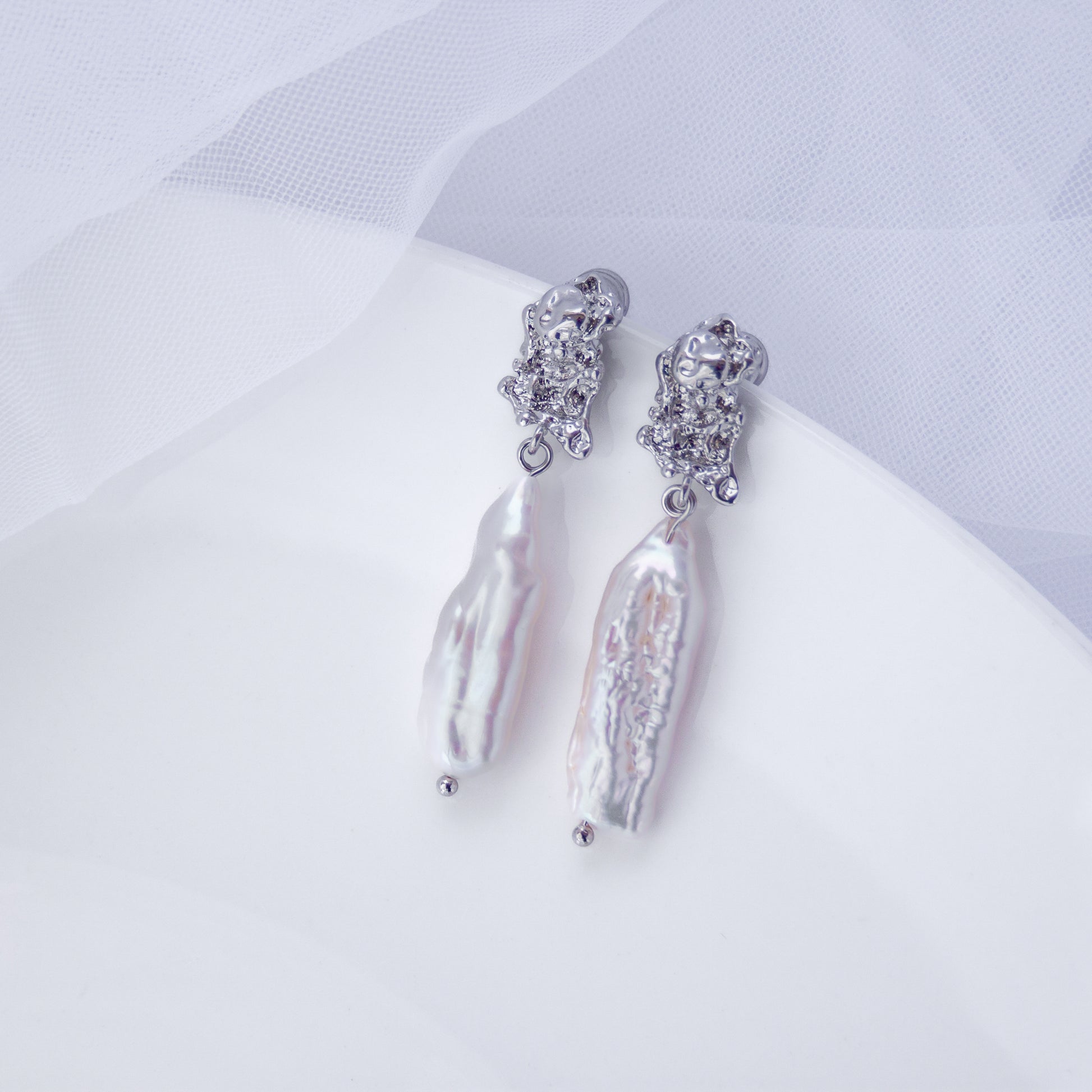 Long silver drop earrings with natural Biwa baroque freshwater pearls on white background.