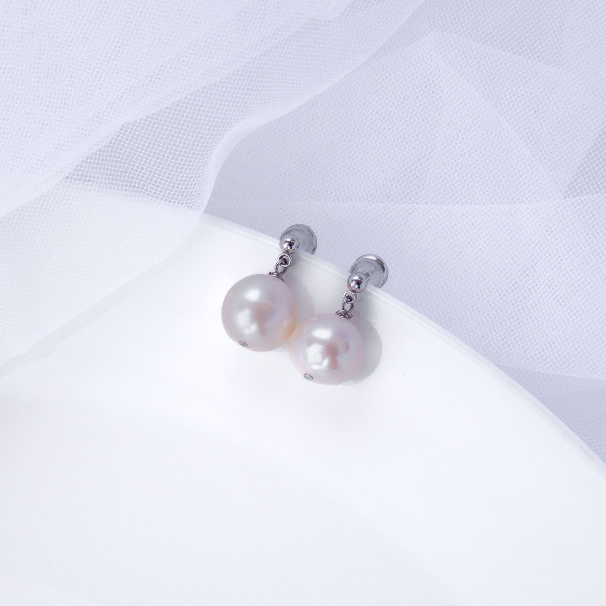 Minimalist stud earrings with real freshwater pearl drops on a white background