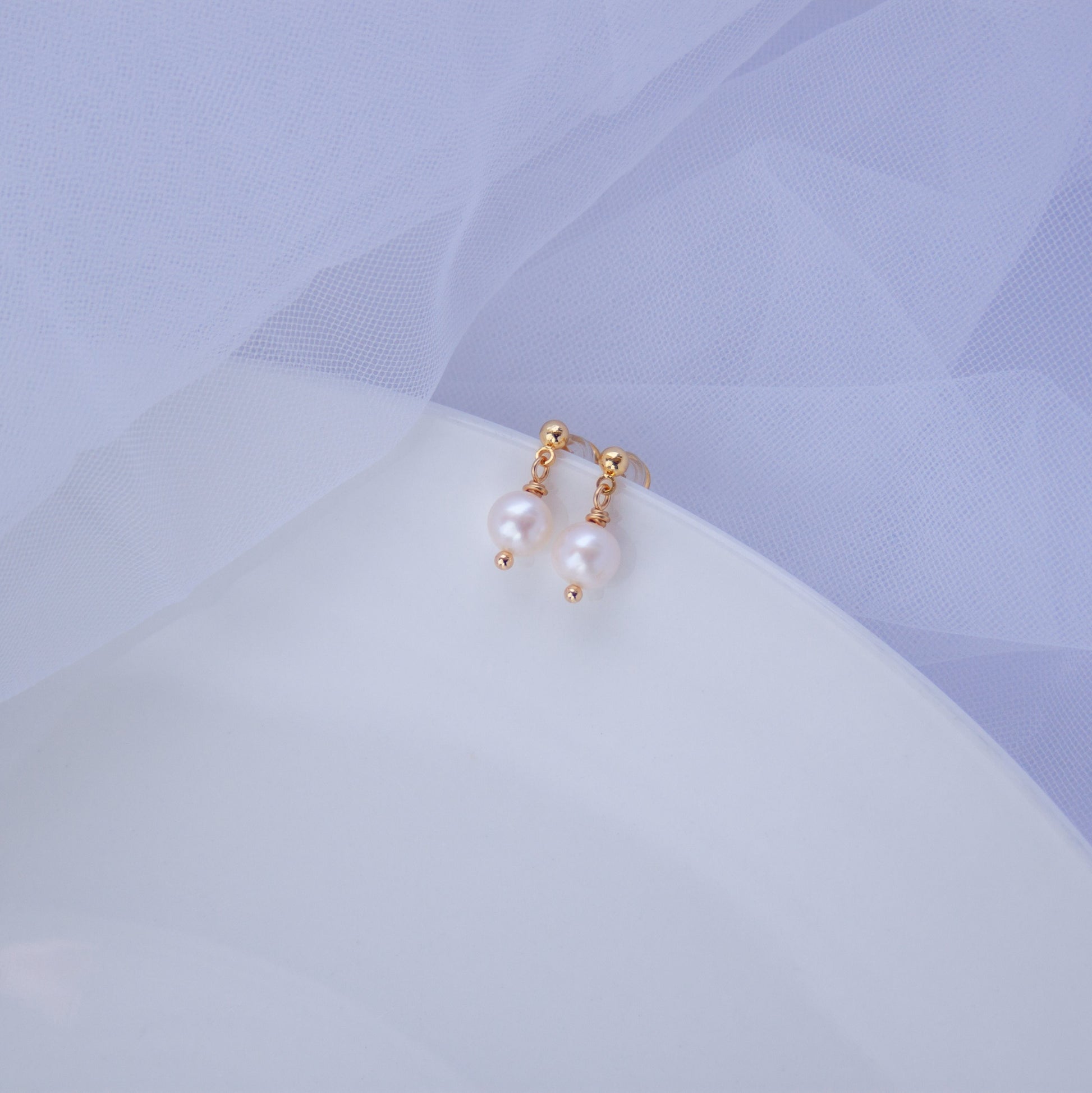 Small freshwater pearl stud earrings with 18K gold accents on a light background