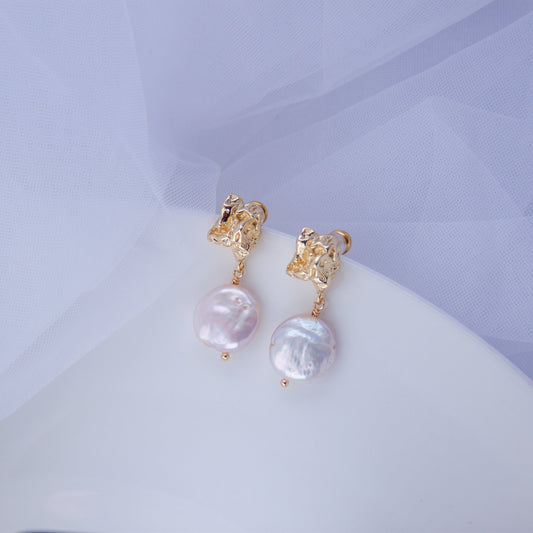 Pair of gold baroque drop earrings with irregular coin pearls on a soft white background