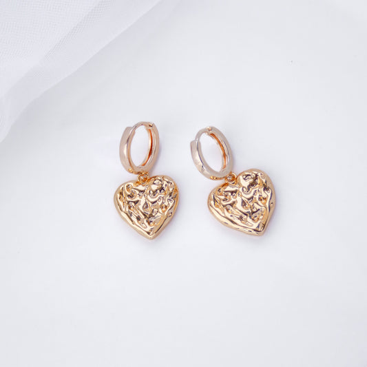 Gold hoop earrings with textured heart-shaped pendants on white background –  romantic jewelry by Pearl Italy