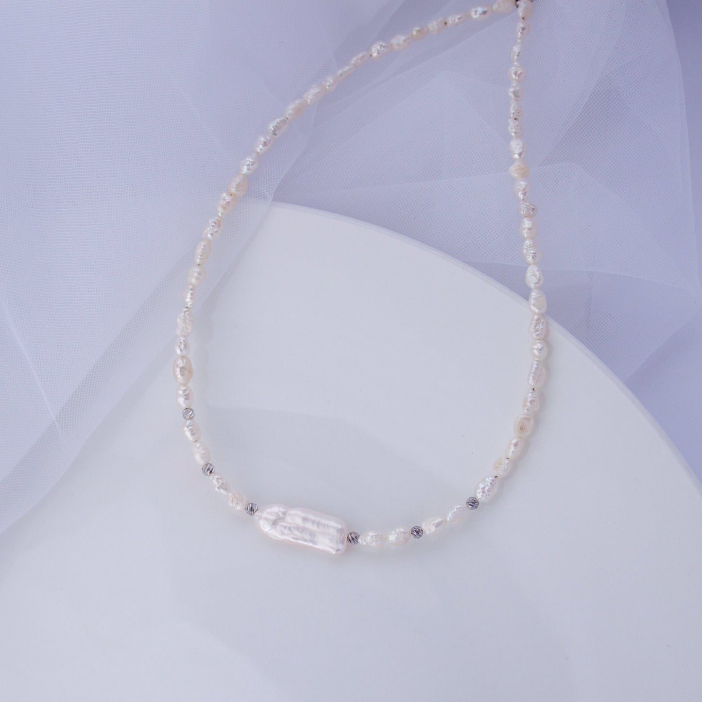Freshwater pearl choker necklace with a long Biwa baroque pearl on a soft background