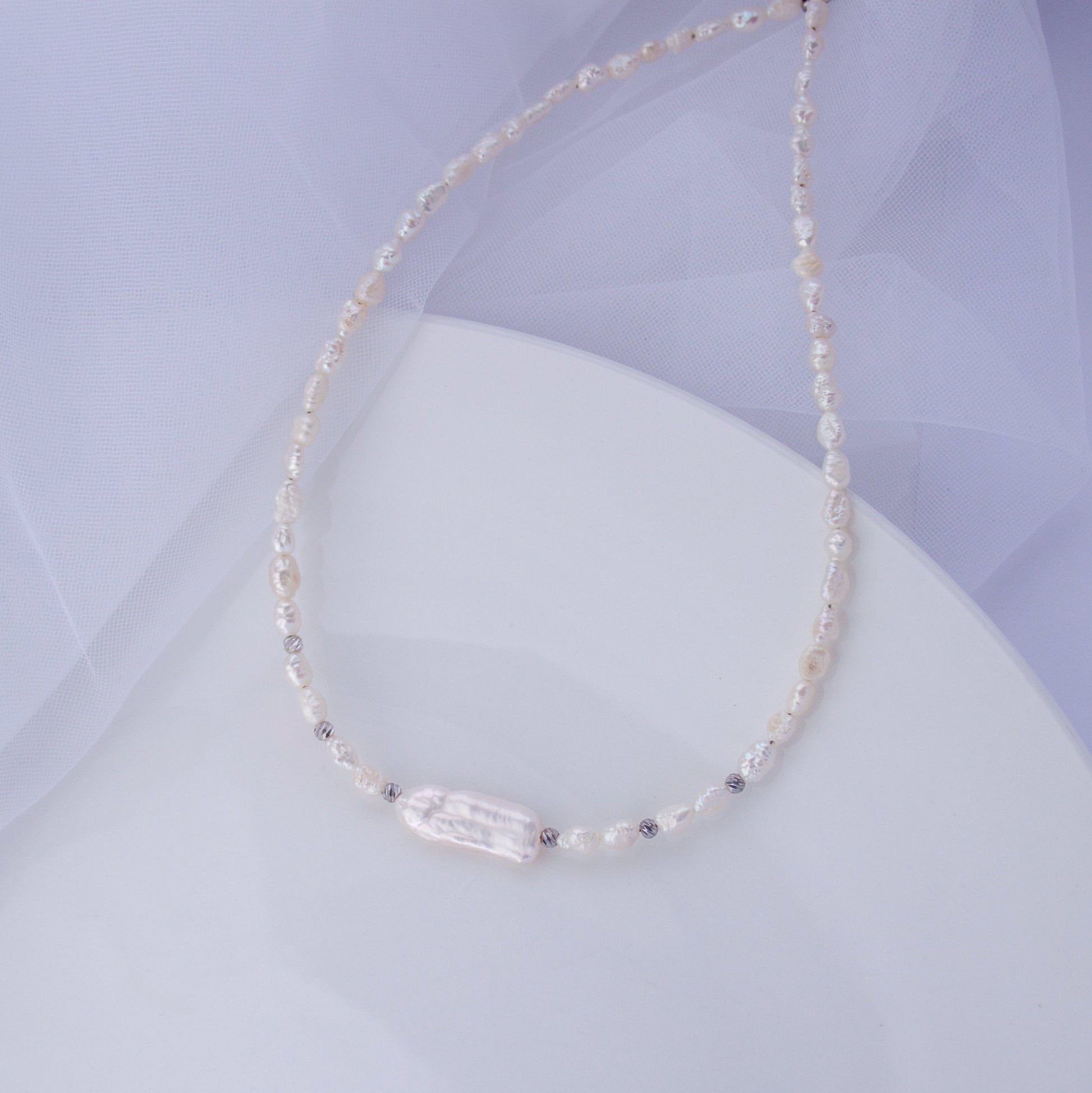 Freshwater pearl choker necklace with a long Biwa baroque pearl on a soft background