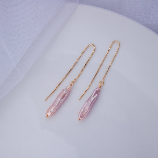 A pair of gold-plated silver chain earrings with pink baroque pearl threaders, displayed on a white surface.