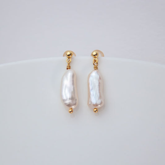 Pair of pearl earrings with gold accents on a light gray background