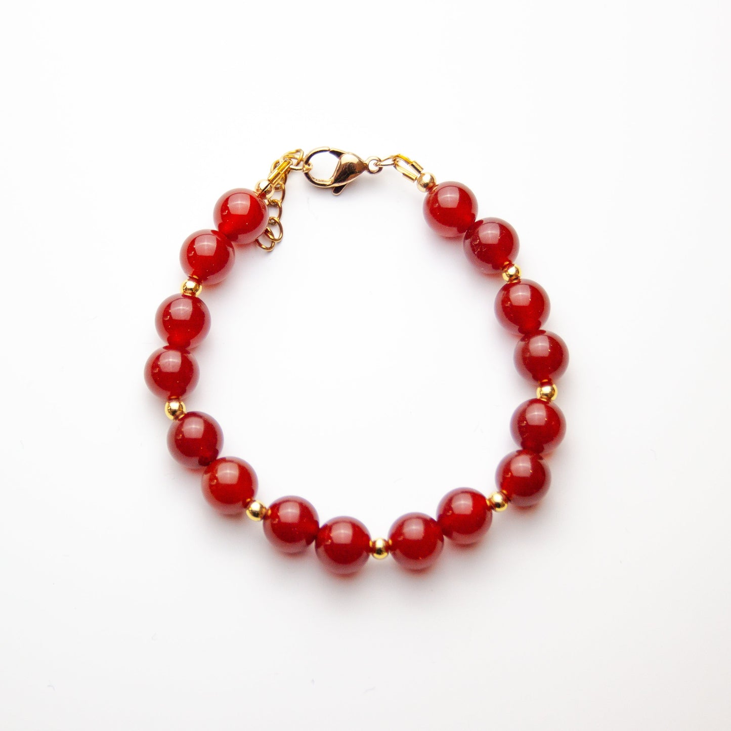 Carnelian bracelet with gold beads on white background