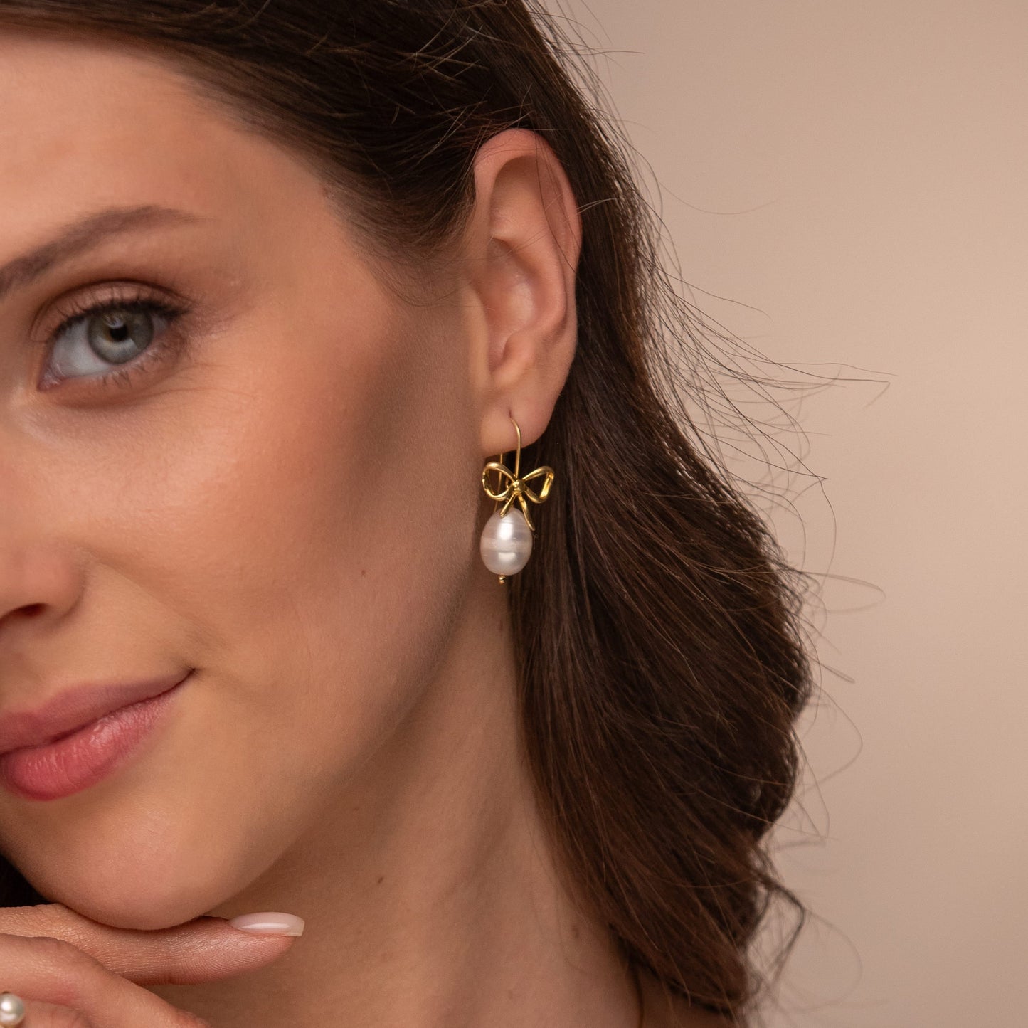 Woman wearing a necklace and earrings with a beige background