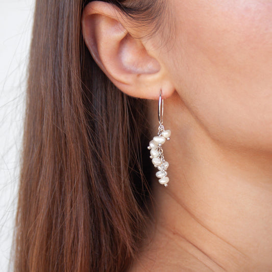 Silver cluster pearl drop earrings with freshwater pearls worn on ear.