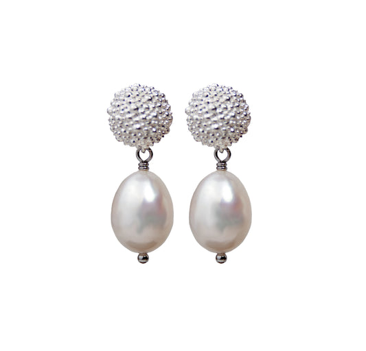 Pair of earrings with pearl drops and textured silver tops on a white background