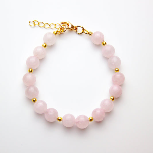 Rose quartz bracelet with gold beads on white background