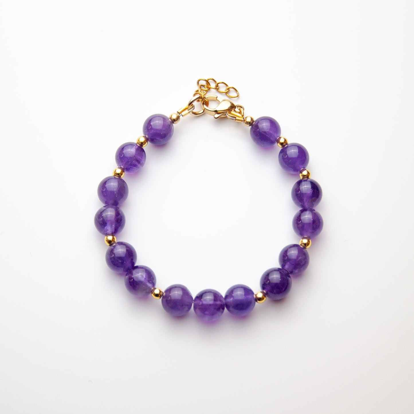 Amethyst bracelet with gold beads on white background