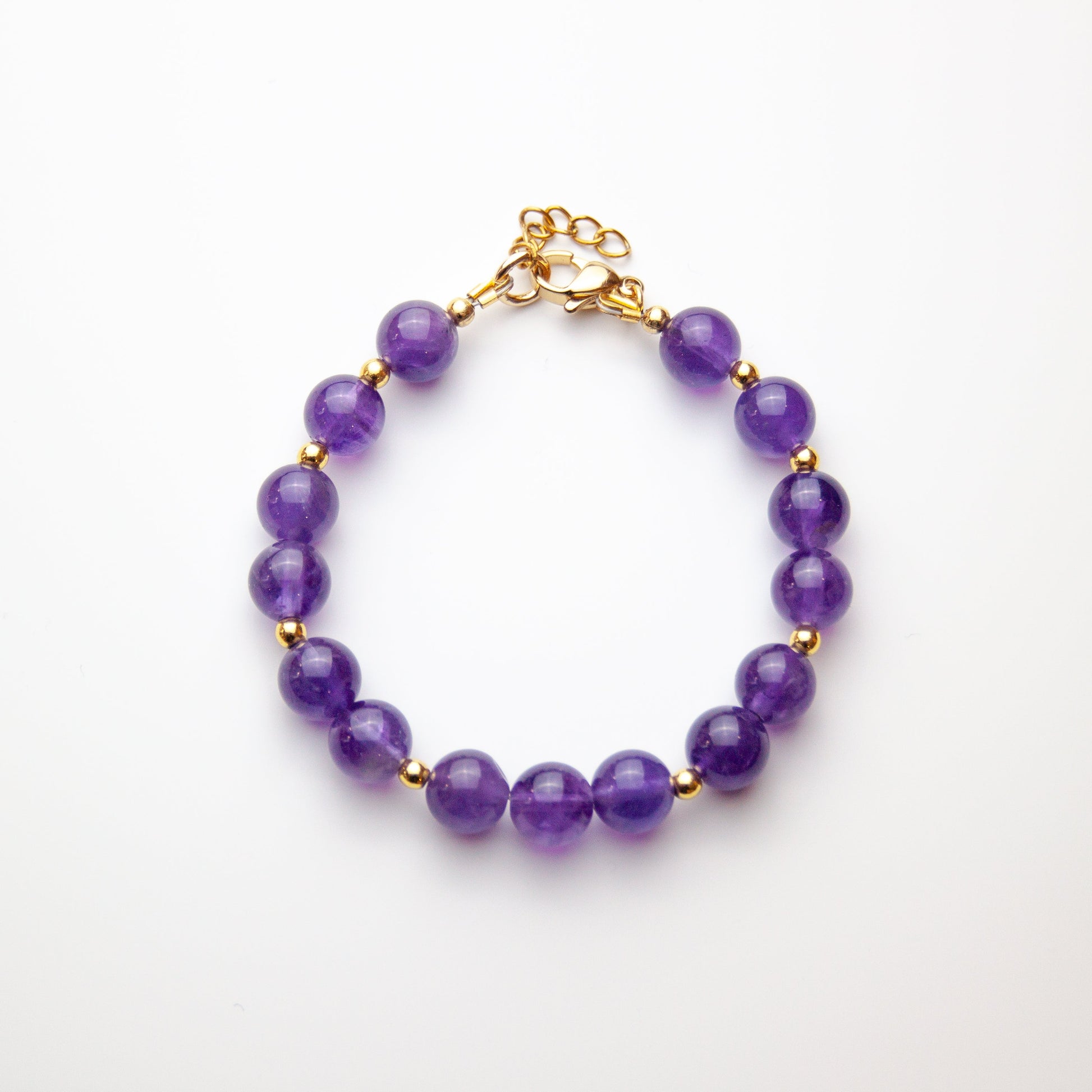 Amethyst bracelet with gold beads on white background