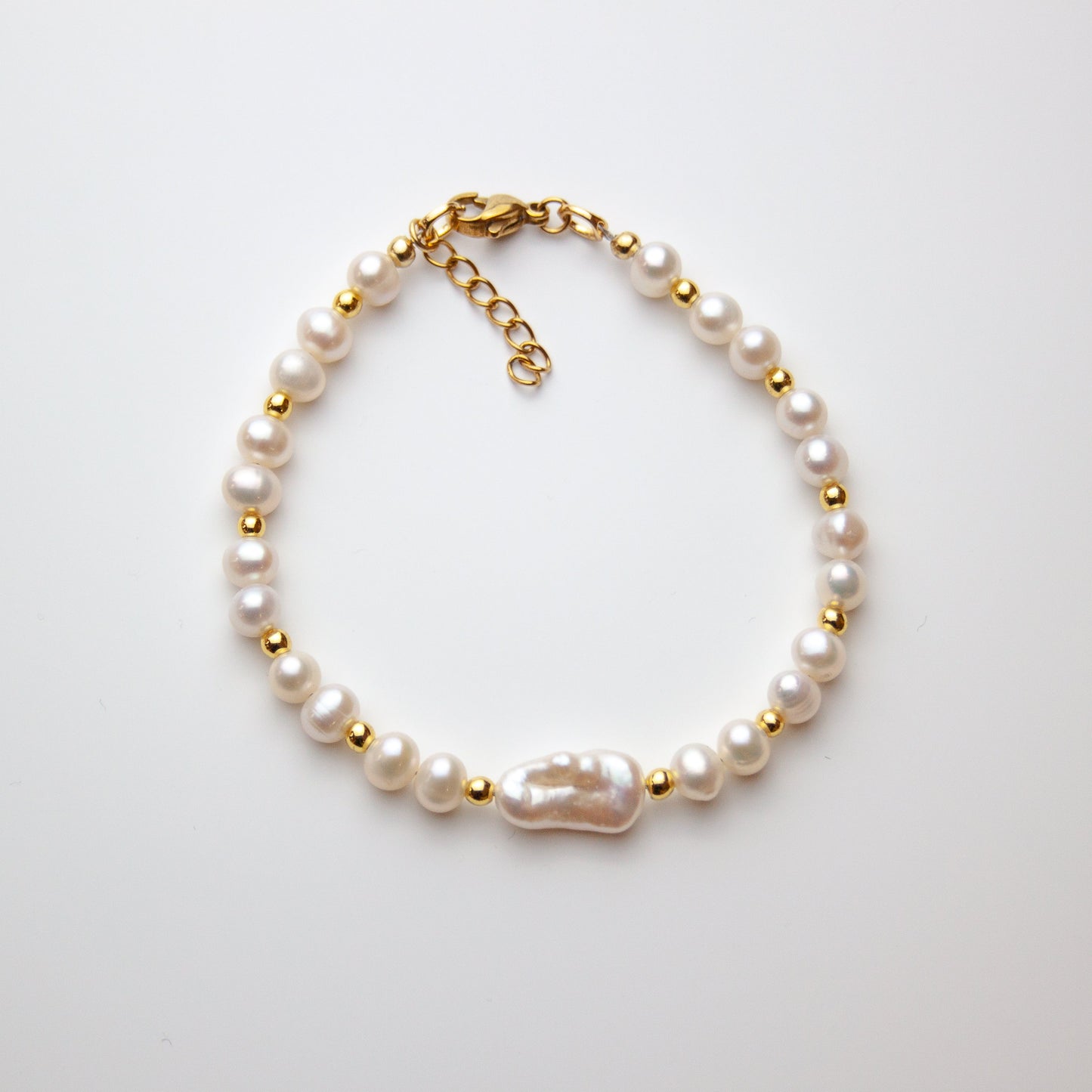 Pearl bracelet with baroque pearl and gold beads on white background