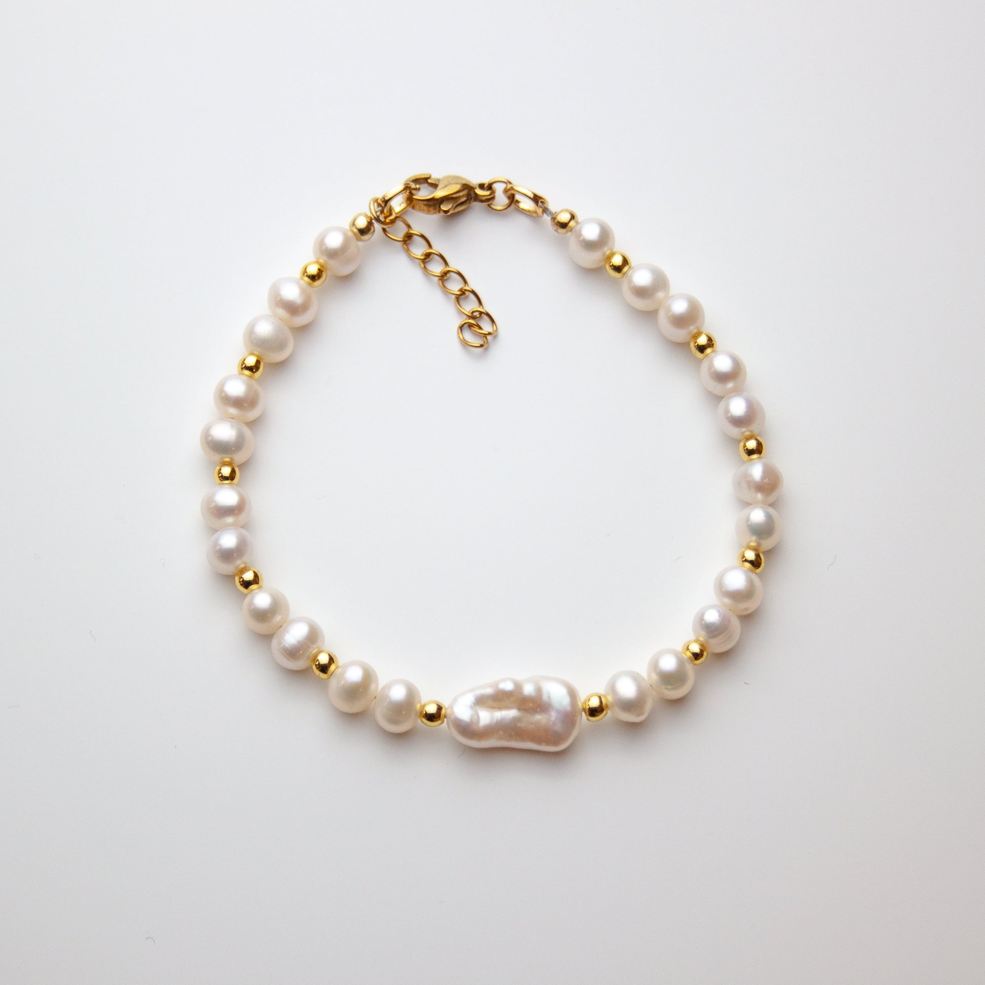 Pearl bracelet with baroque pearl and gold beads on white background