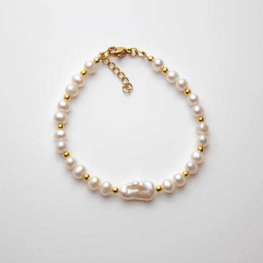 Pearl bracelet with baroque pearl and gold beads on white background