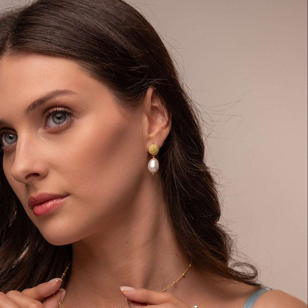 Woman wearing pearl jewelry against a neutral background